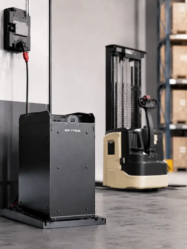 Battery powered Akuros electric stacker truck charging in an indoor warehouse